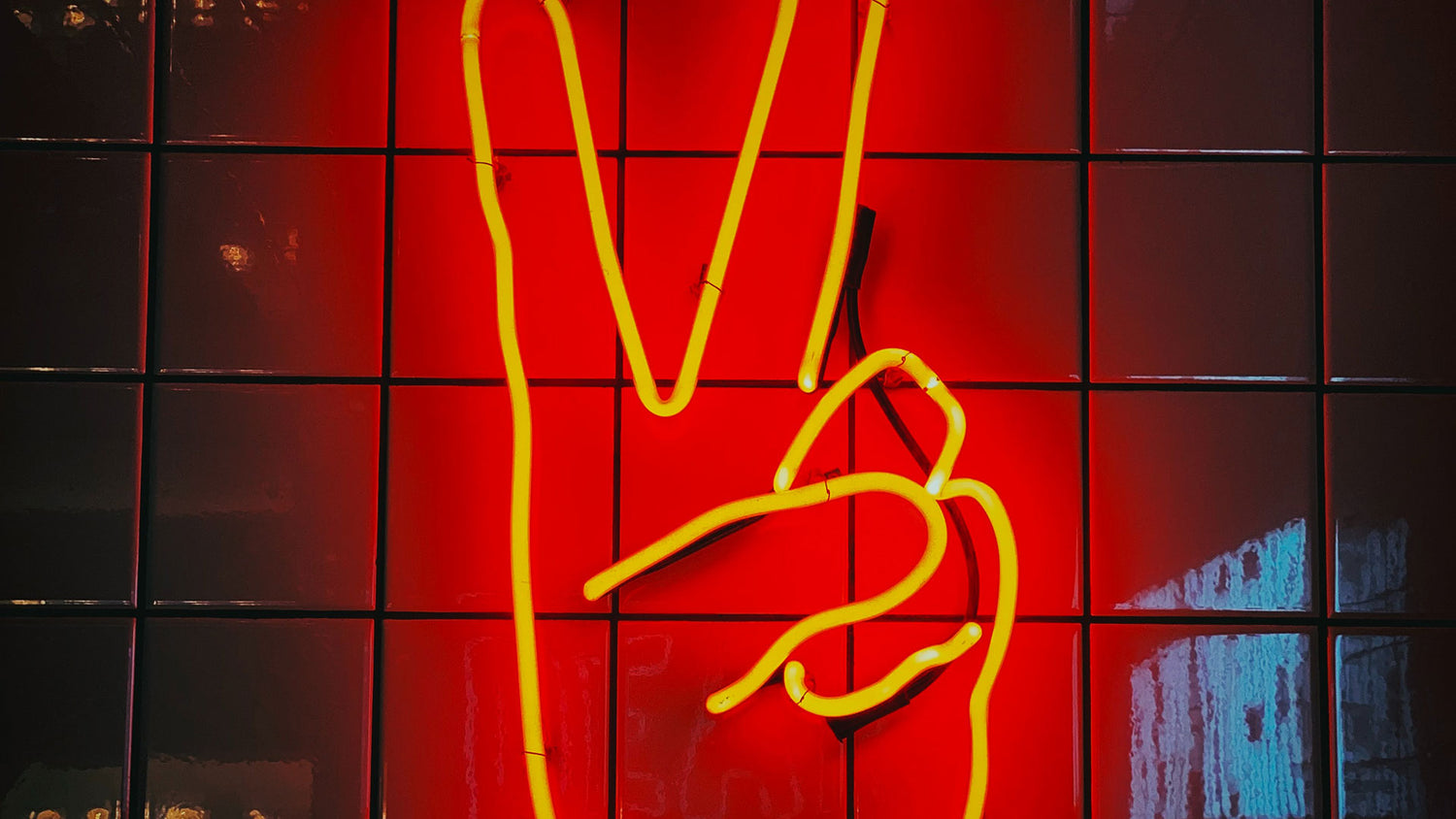 A hand with a Viktory symbol mounted as a red neon installation on a tiled wall