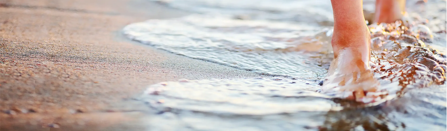Füße im Wasser am Sandstrand