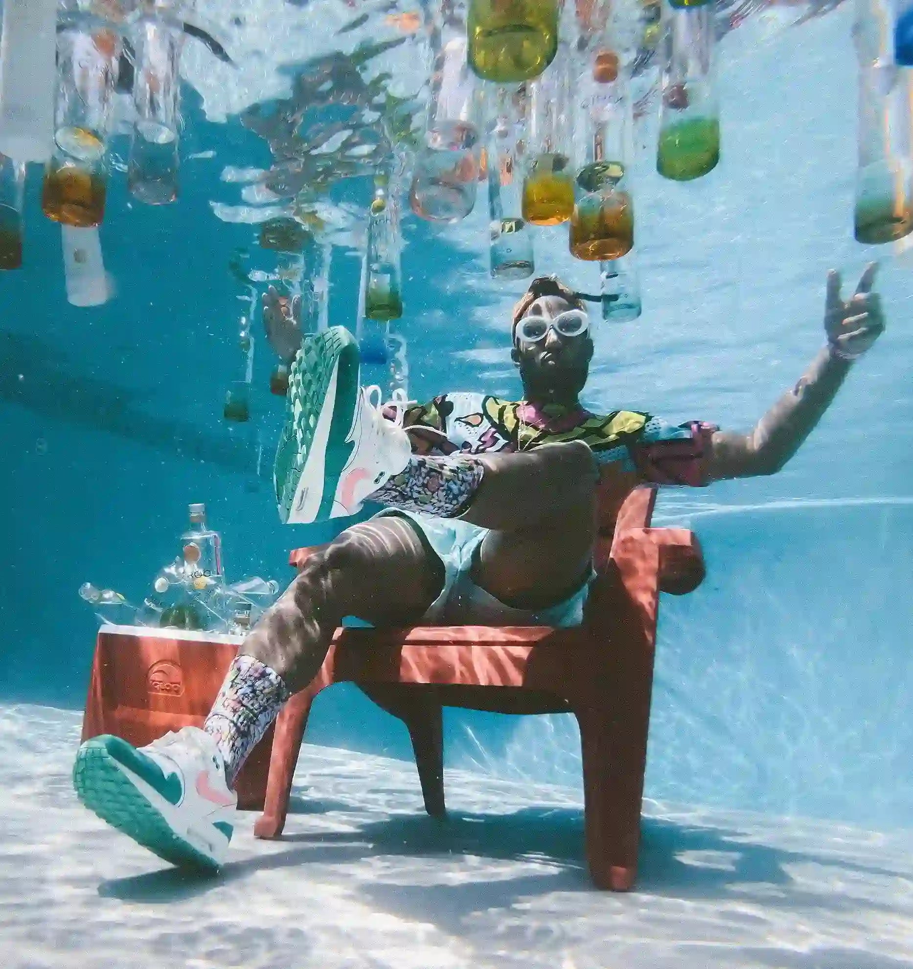 Mann unter Wasser sitzend mit schwimmenden Wasserflaschen