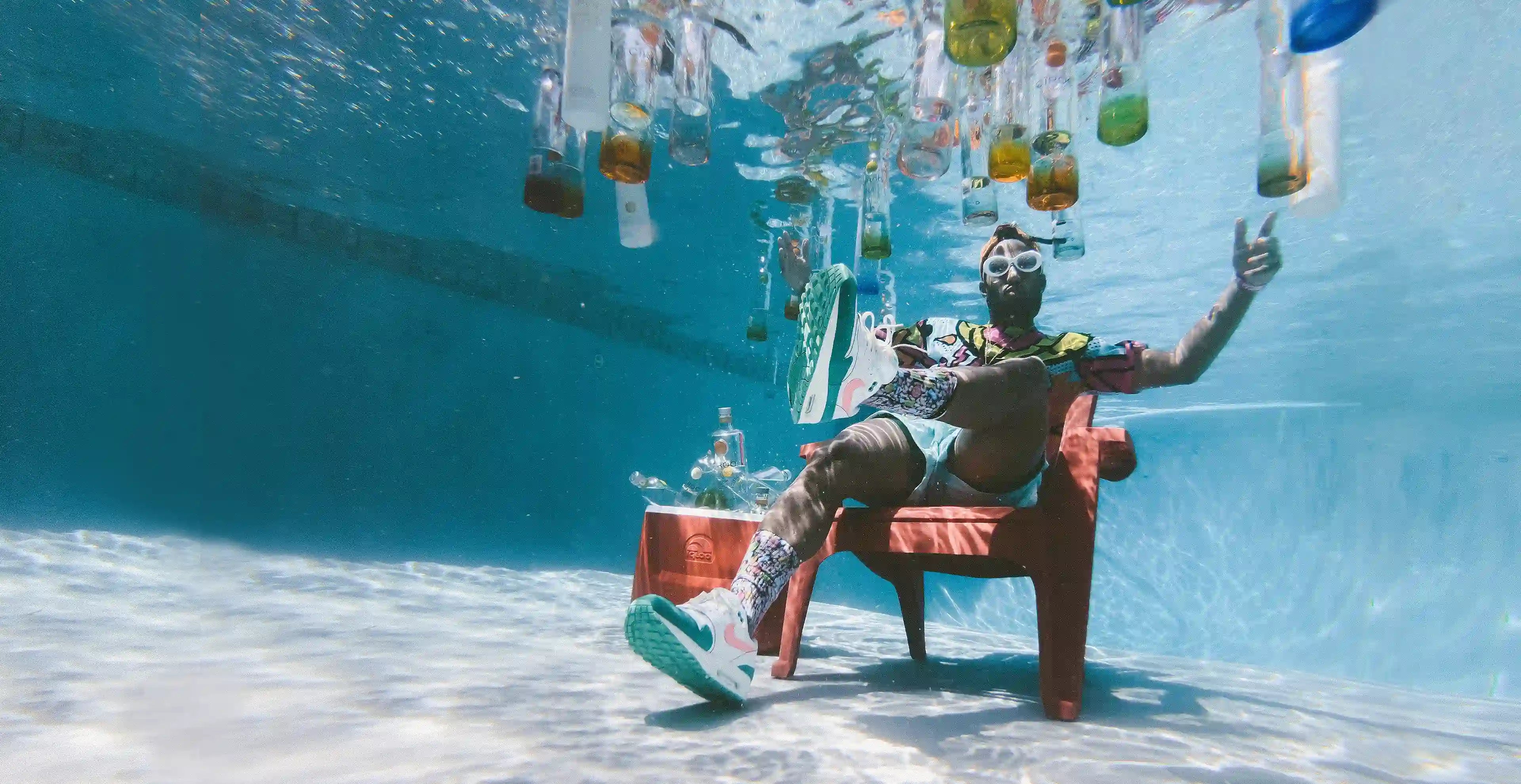 Mann unter Wasser sitzend mit schwimmenden Wasserflaschen